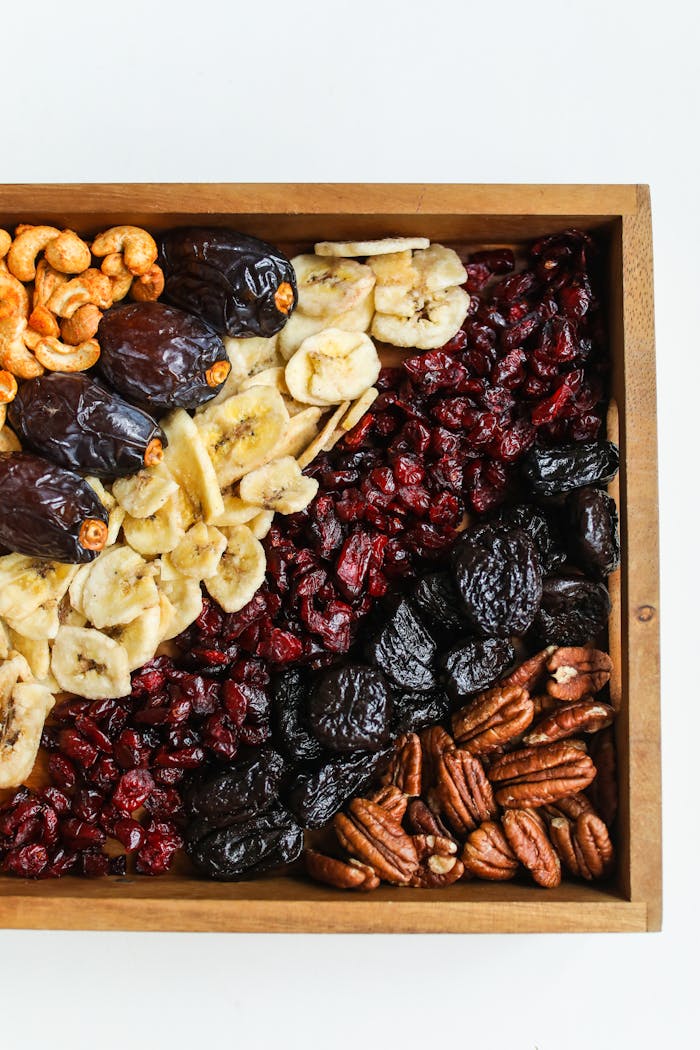 Services-03 Top view of a wooden tray filled with assorted dried fruits and nuts, offering a healthy snack.