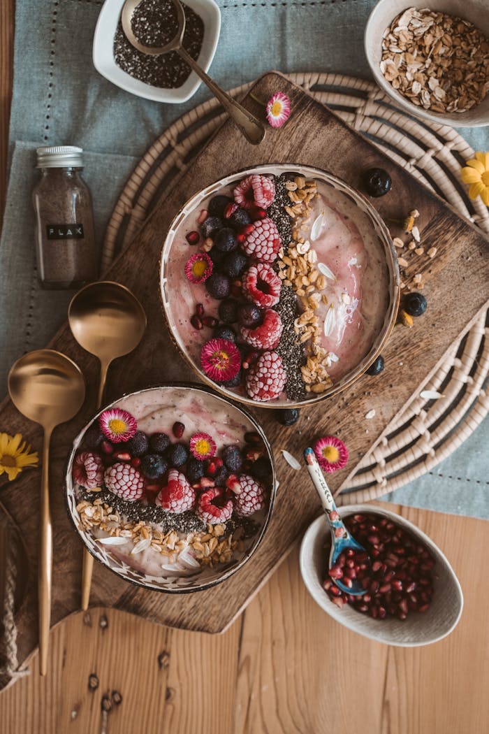 digital Top view of nutritious smoothie bowls with berries, chia seeds, and oats on a wooden table.