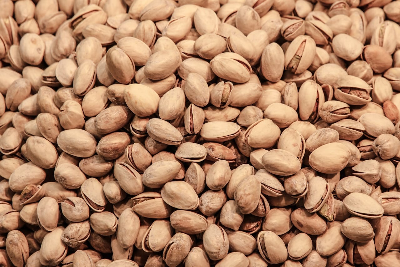 A detailed close-up image of pistachio nuts, showcasing their natural texture and earthy tones.